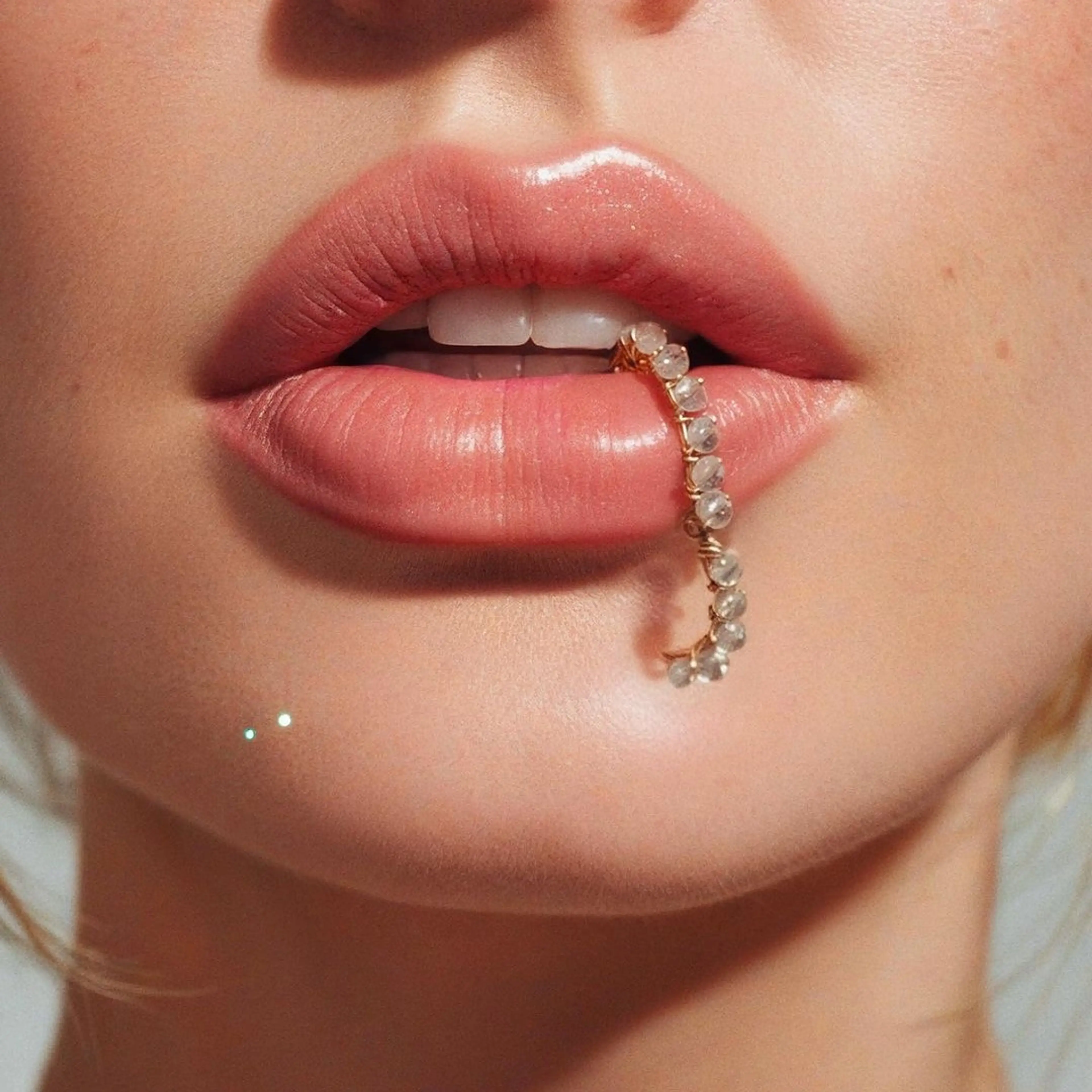 Close-up of lips holding a pearl earring