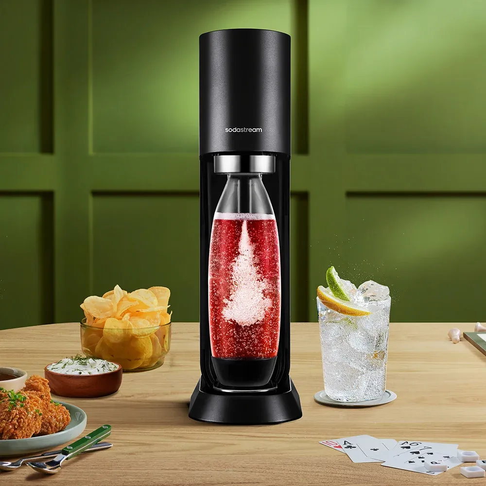 A SodaStream machine on a wooden counter next to a glass